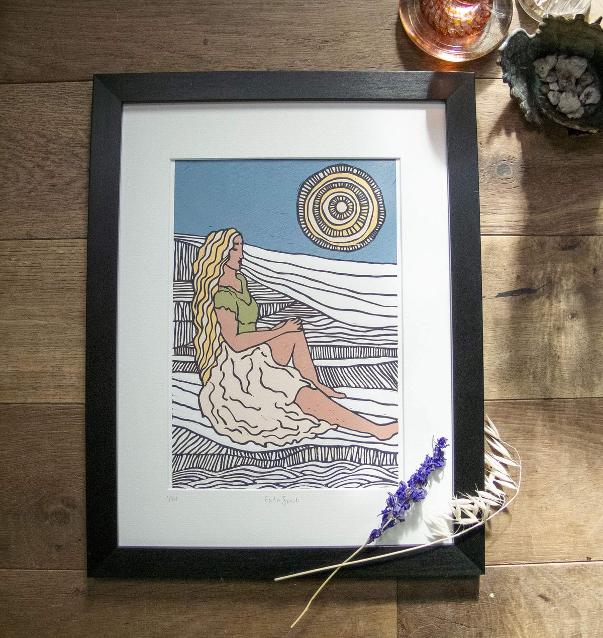 Greek Mythology linocut print depicting a seated goddess with long golden hair, flowing pale robes and a patterned sun