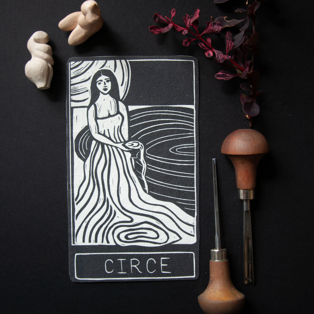 Tarot card featuring a woman labeled 'Circe' on a dark background with tools and stones.