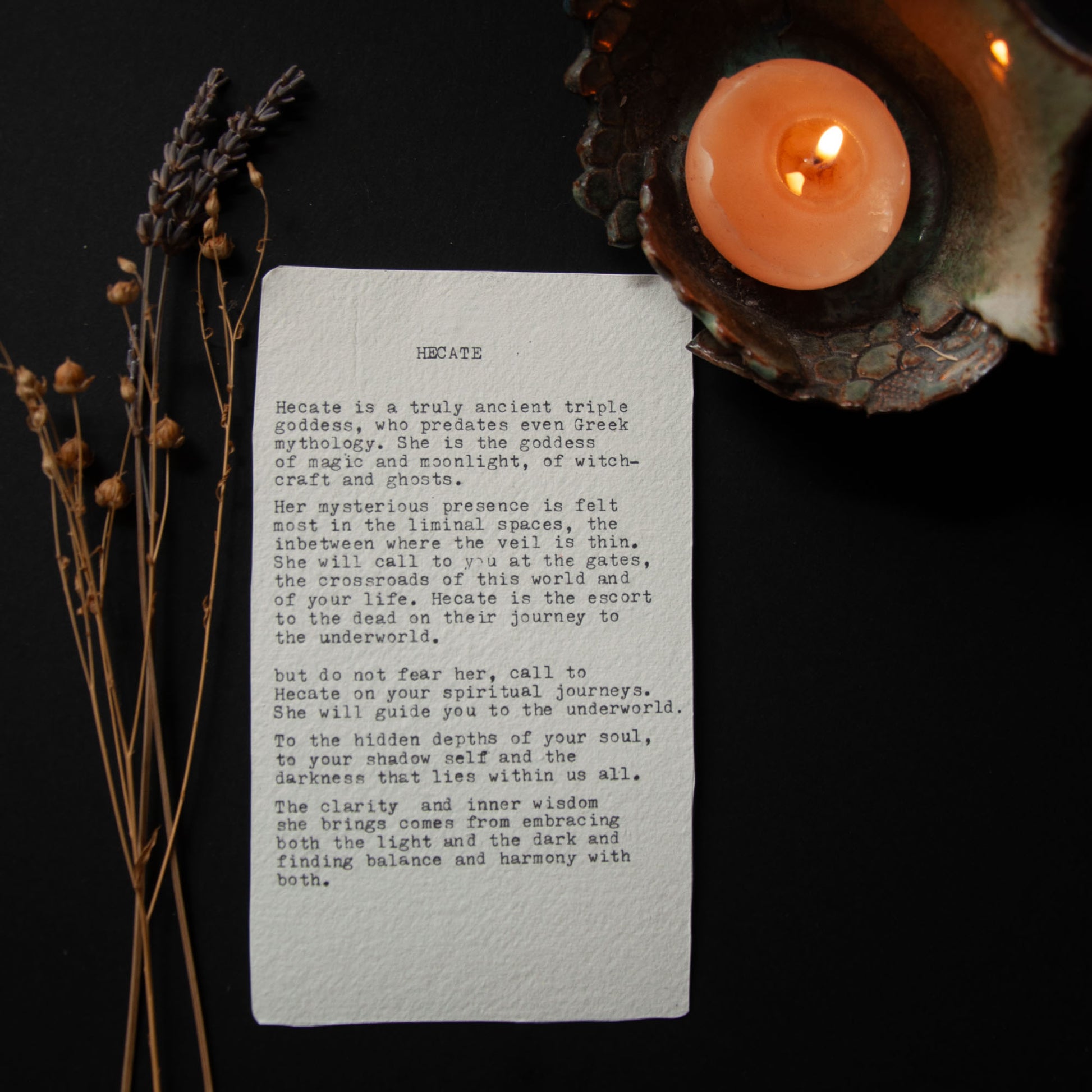 Sheet of paper with text, candle, and dried plants on a dark background