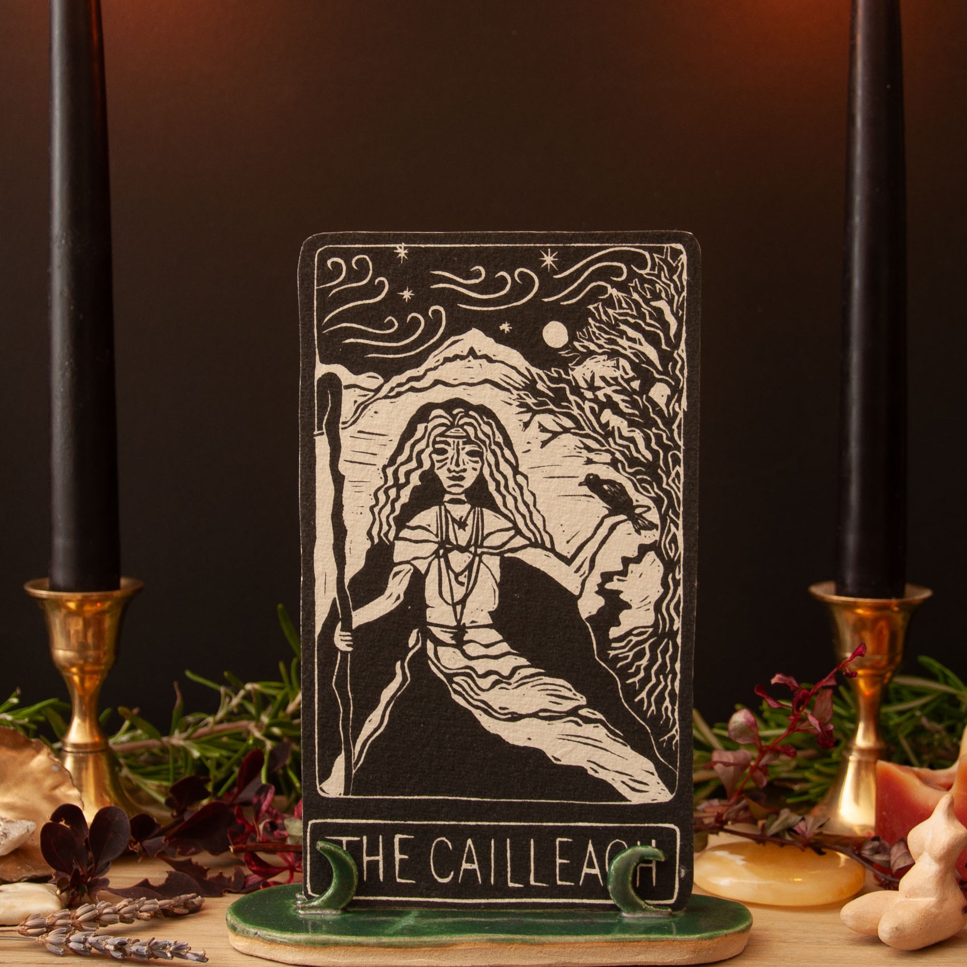 Tarot card titled 'The Cailleach' with a woman and wolf illustration, surrounded by candles and herbs.