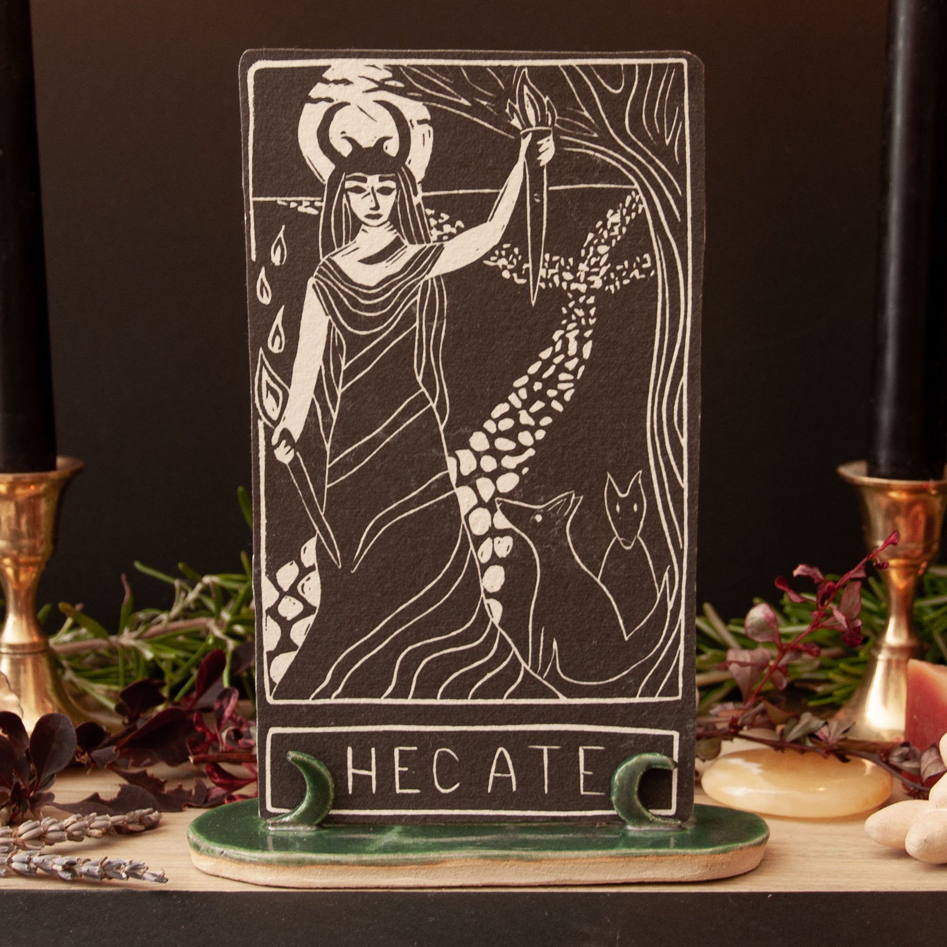 Tarot card featuring Hecate with candles and herbs on a dark background
