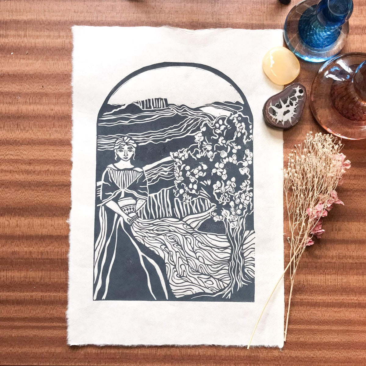 ANAHIT | ARMENIAN GODDESS linocut print in deep blue-grey, depicting a woman beside a flowering tree and flowing landscape