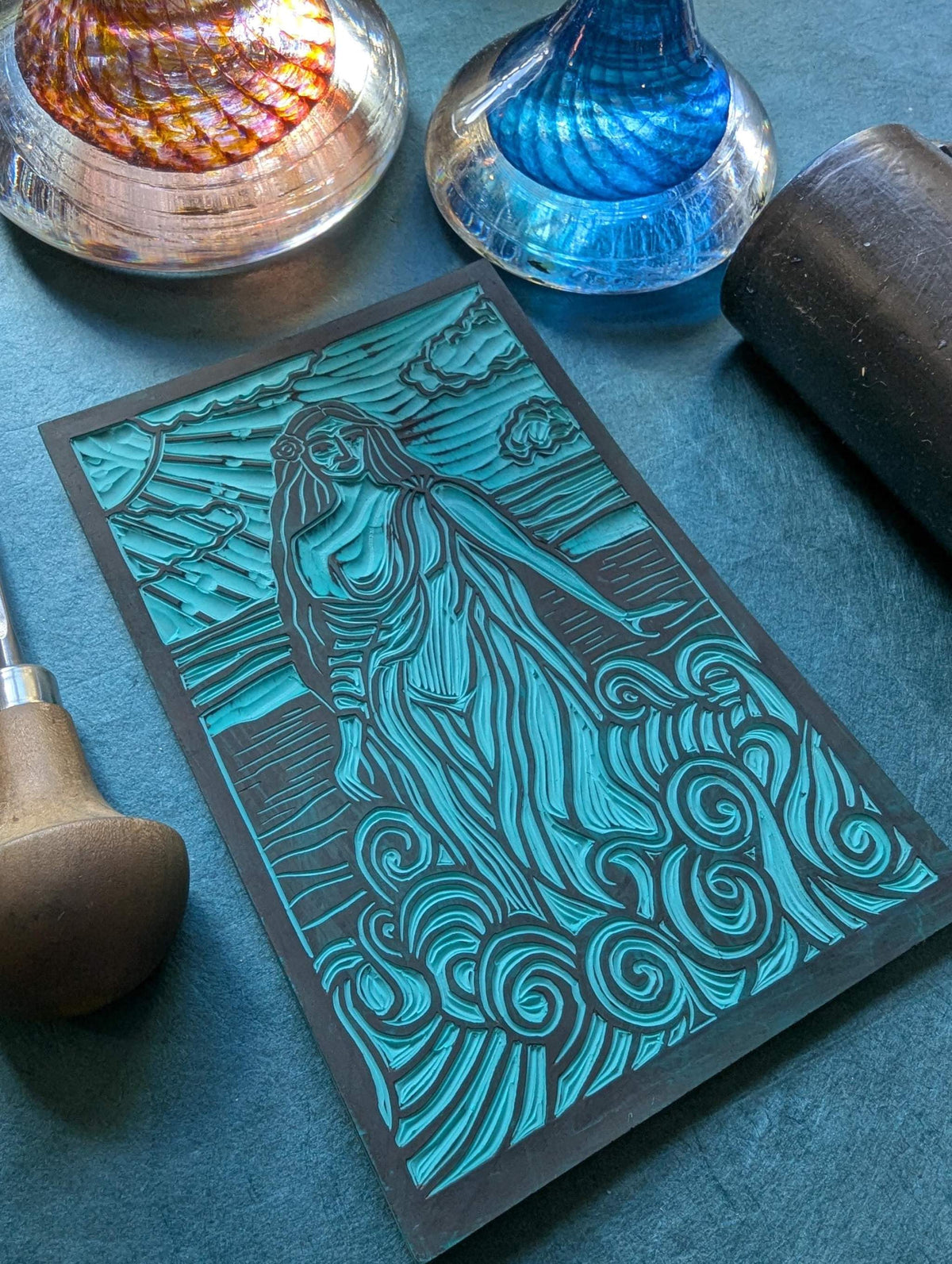 APHRODITE ALTAR CARD with a teal and black linocut-style goddess, flowing hair and swirling wave patterns