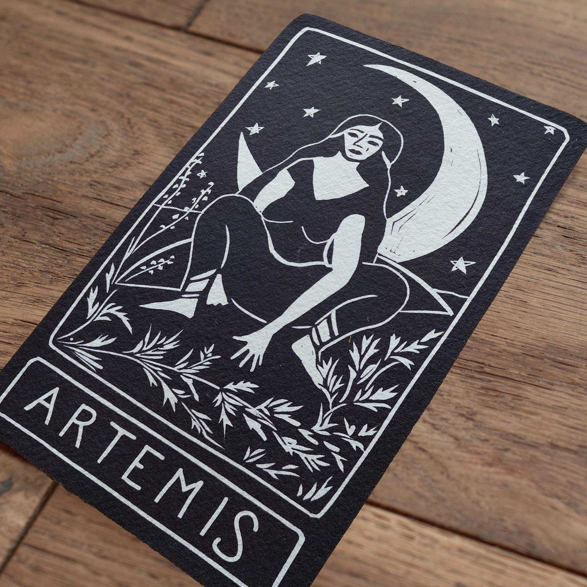 ARTEMIS ALTAR CARD in black cotton rag card, featuring a white linocut of Artemis beneath a crescent moon and stars