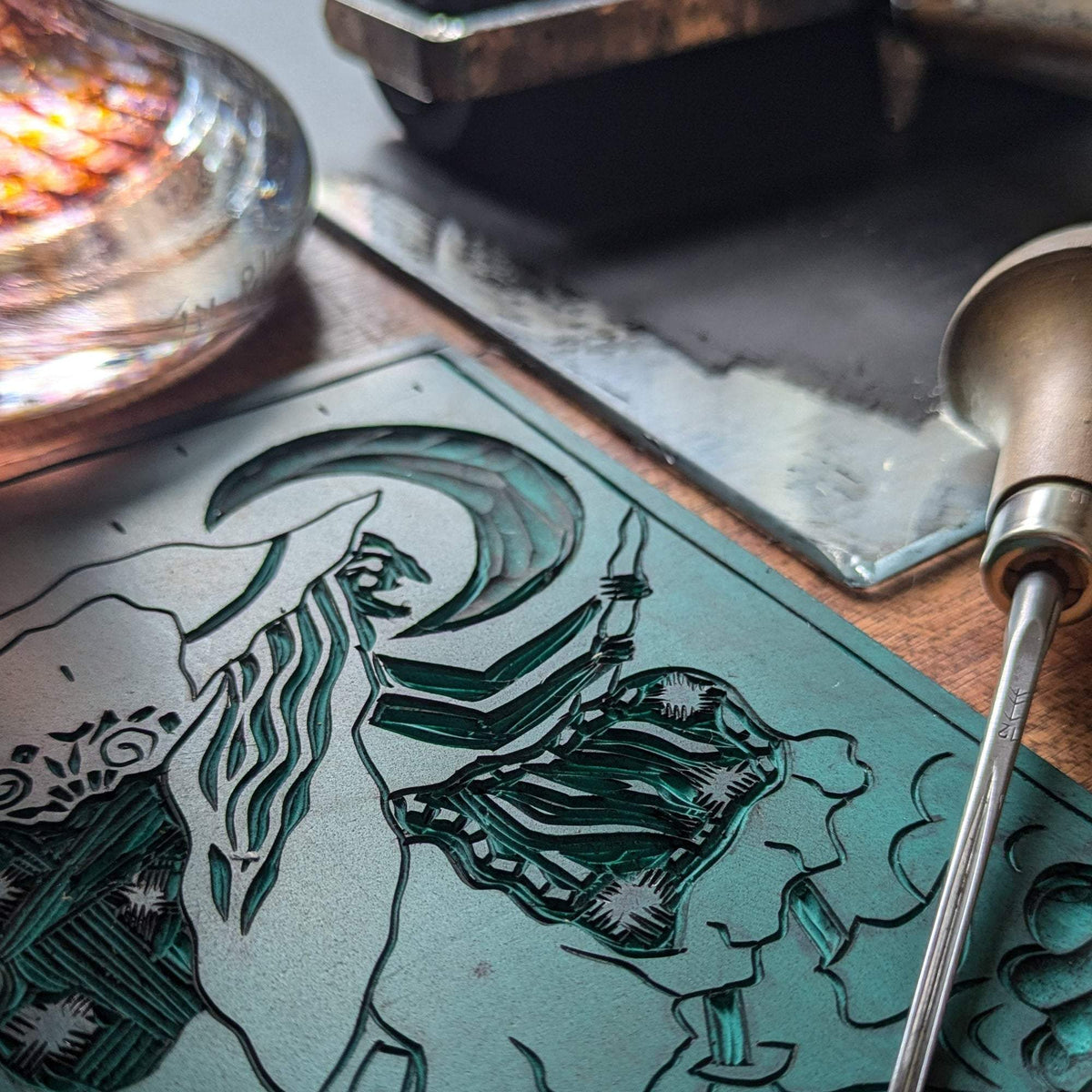 BEFANA ORACLE CARD with black linocut artwork on a teal printing block, showing a witch with flowing hair and a broom.