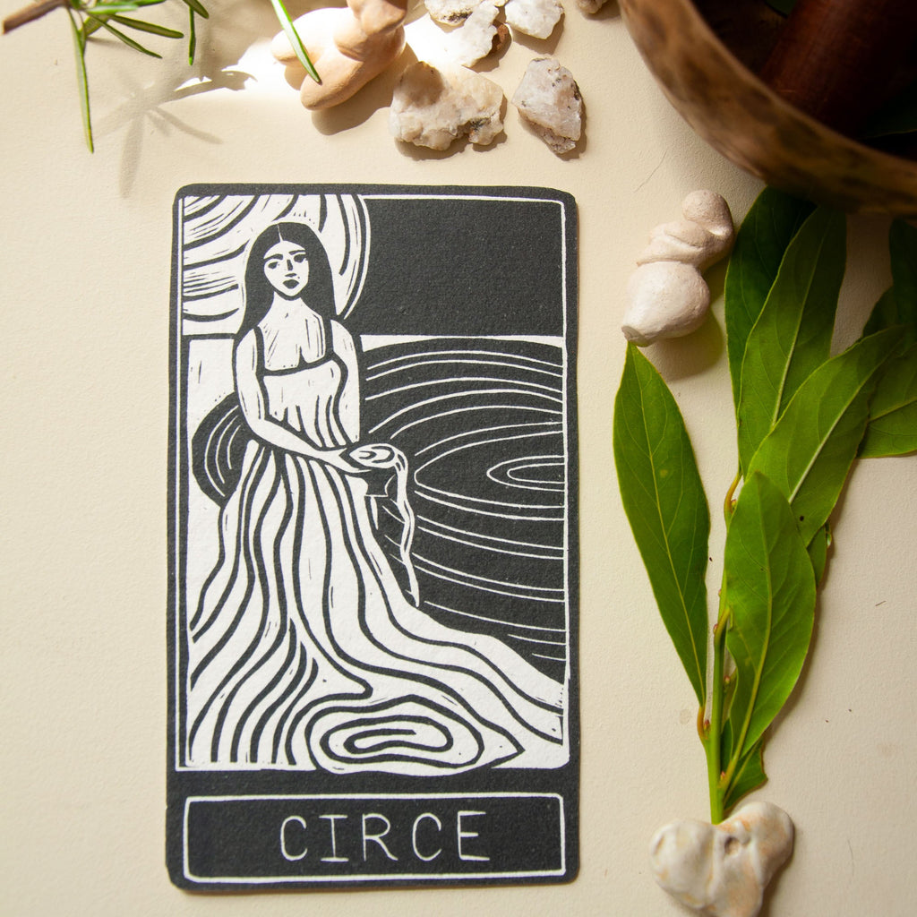 CIRCE ORACLE CARD featuring a black-and-white handmade linocut of a robed goddess beside flowing water