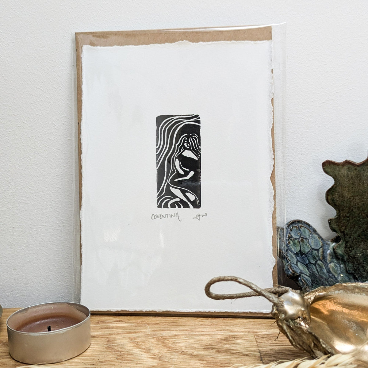COVENTINA BRITISH WATER GODDESS miniature black linocut print on white paper, showing a flowing-haired figure