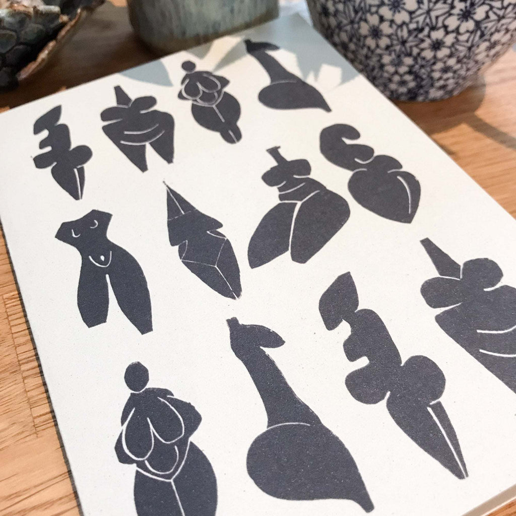 DANCING GODDESSES greeting card with charcoal-black linocut silhouettes of prehistoric female figurines on cream cardstock