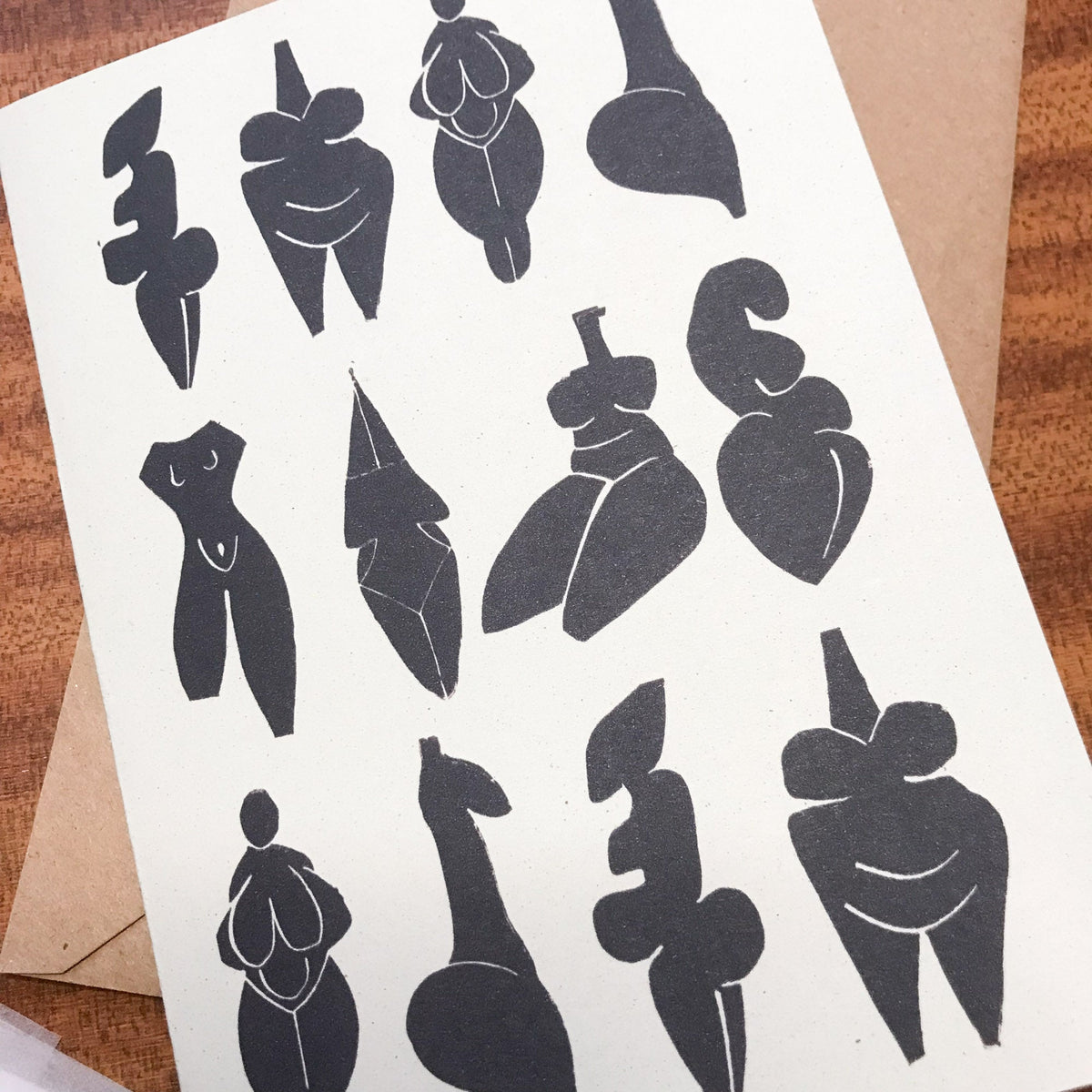 DANCING GODDESSES greeting card in cream recycled cardstock, featuring a black linocut of abstract prehistoric female figures