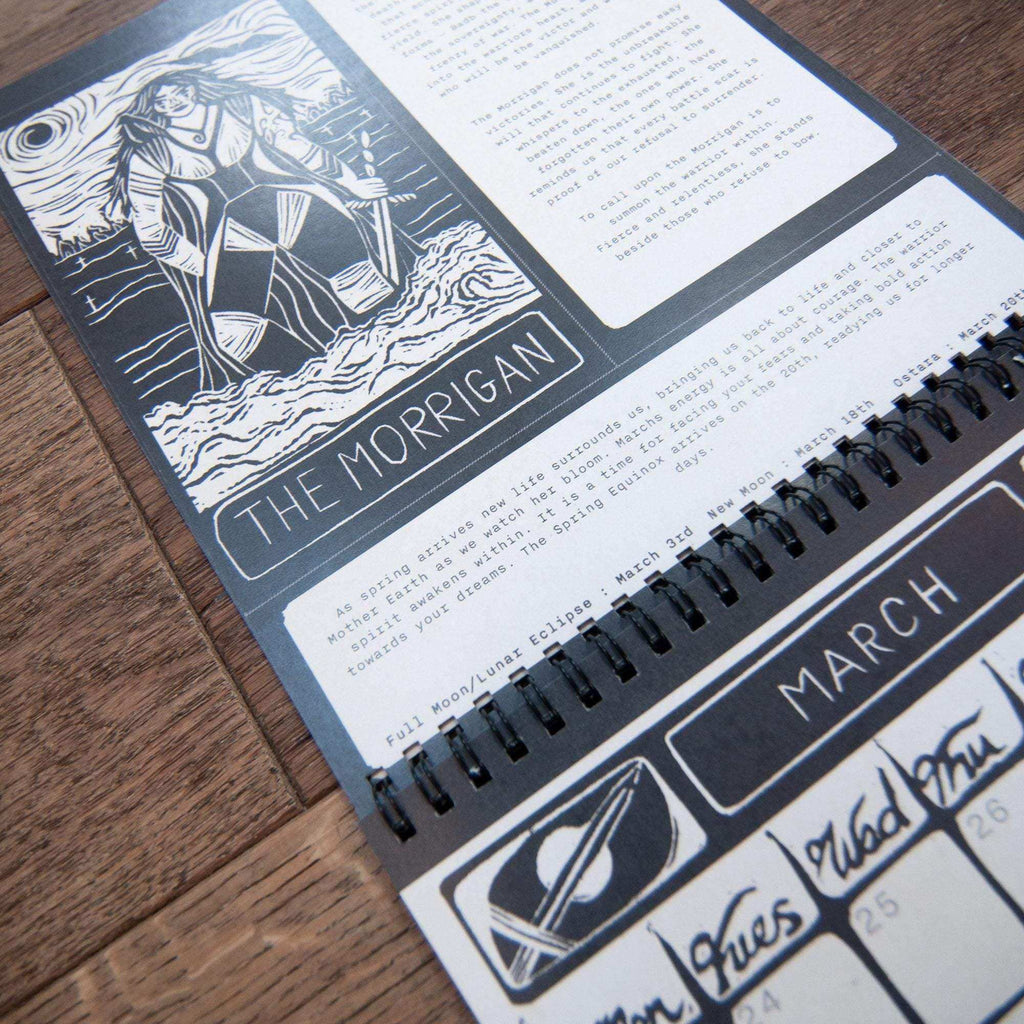 Dark Goddess Calendar 2027 with black spiral binding, pale paper pages and monochrome linocut art of The Morrigan