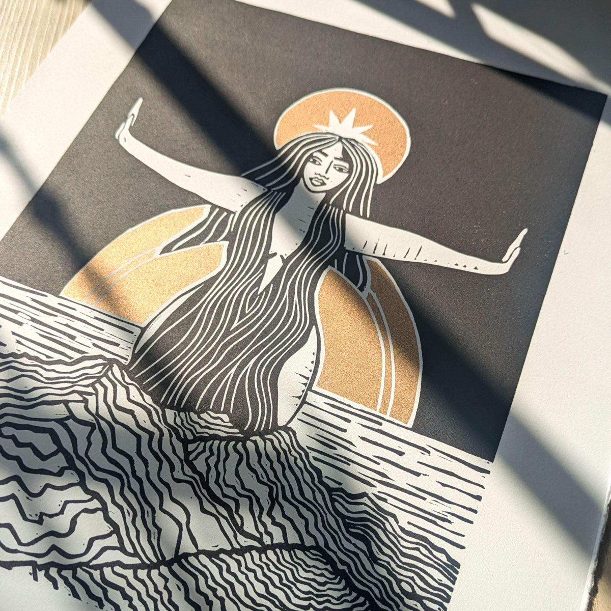 Divine Sophia Art linocut print featuring a black-and-cream goddess with flowing hair, orange halo and waves