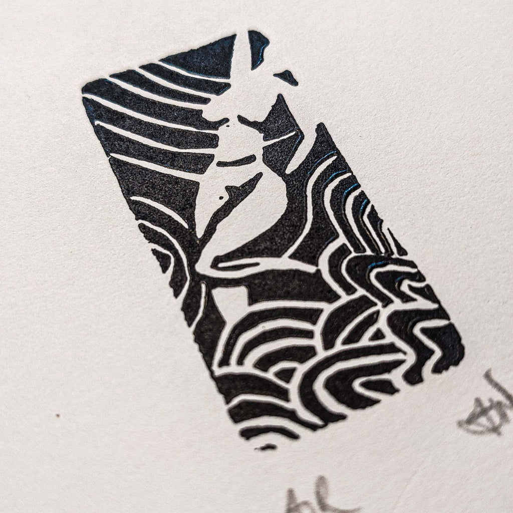 ELEMENTAL GODDESS miniature linocut print in black ink, featuring an abstract face framed by flowing, striped shapes