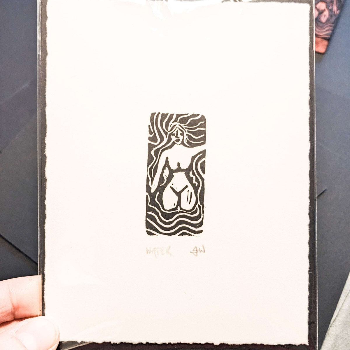 ELEMENTAL GODDESS miniature linocut print in black ink on cream paper, featuring a nude female figure amid flowing lines