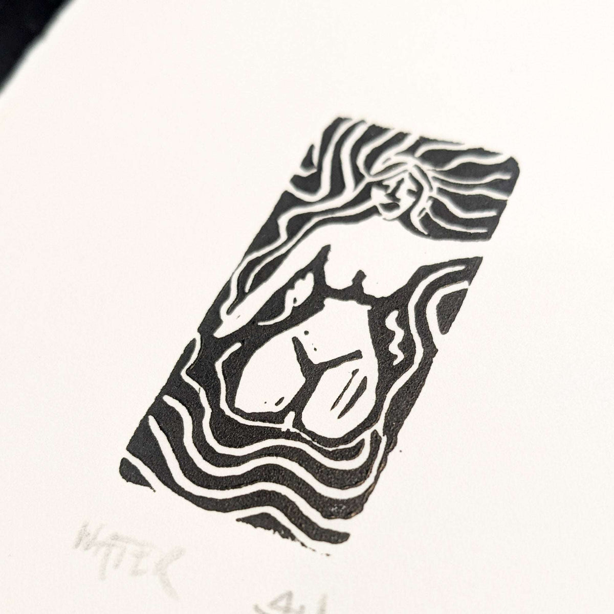 ELEMENTAL GODDESS miniature linocut print in black ink, featuring a flowing-haired figure within bold wavy lines