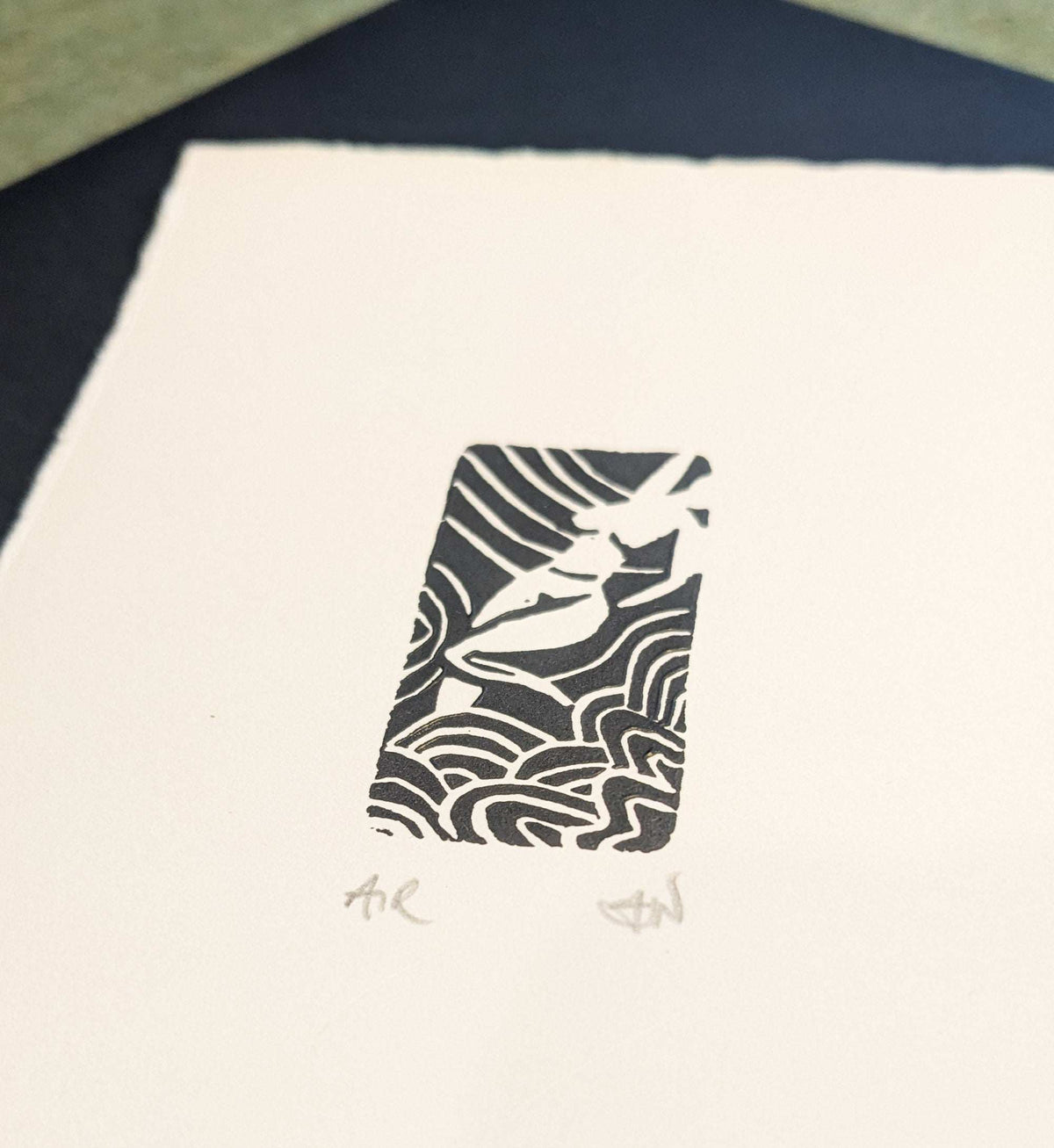 ELEMENTAL GODDESS miniature linocut print in black ink on cream paper, featuring a bird among flowing wave-like lines