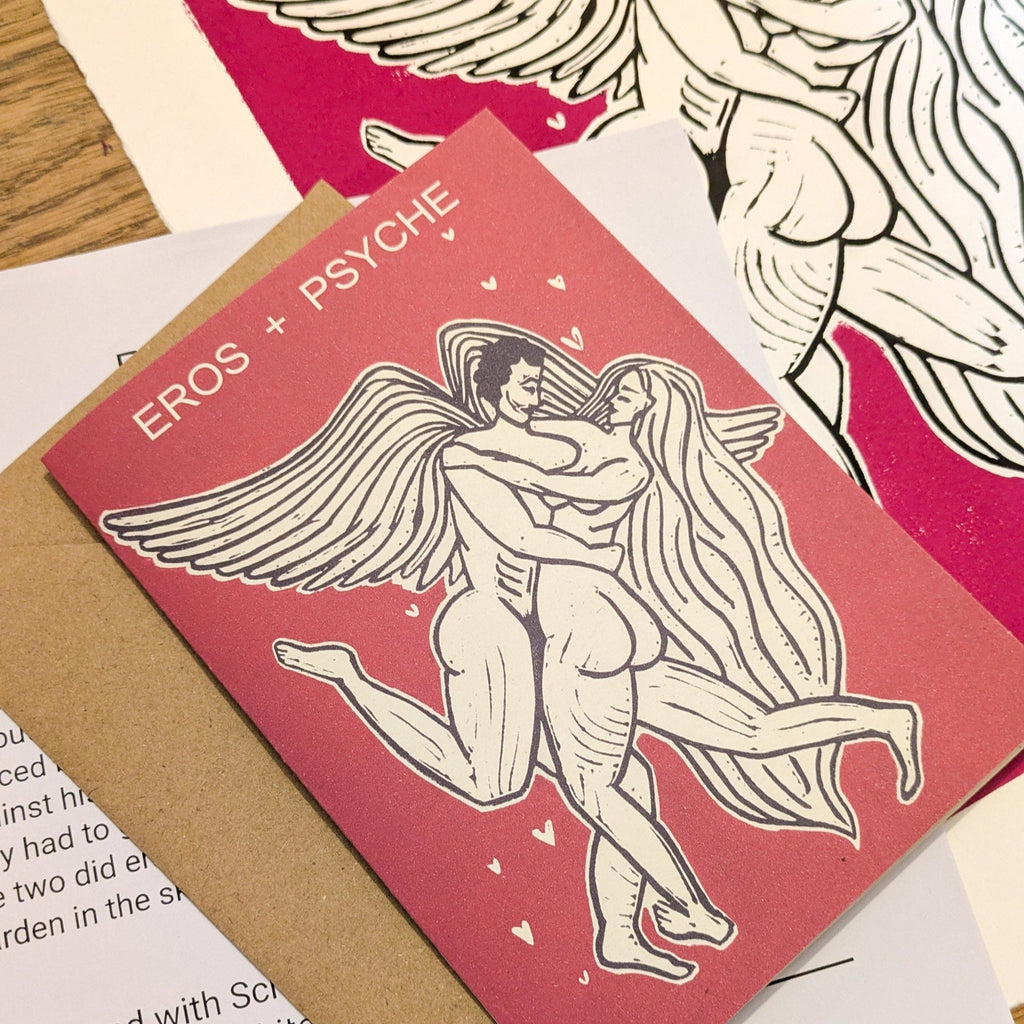 EROS AND PSYCHE Greeting card in muted red cardstock, with a cream-and-black linocut of embracing winged figures and hearts.