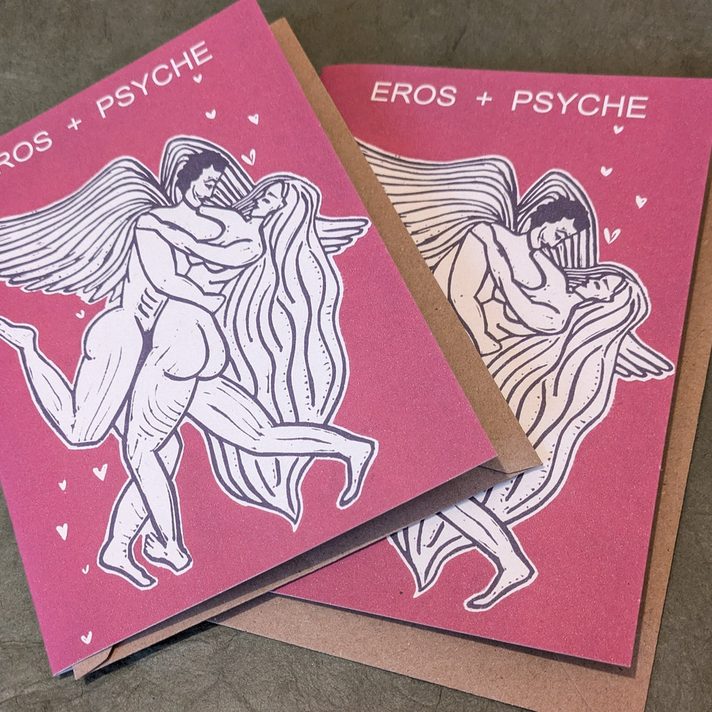 EROS AND PSYCHE Greeting card in pink printed cardstock, with a black-and-white linocut of embracing figures and small hearts.