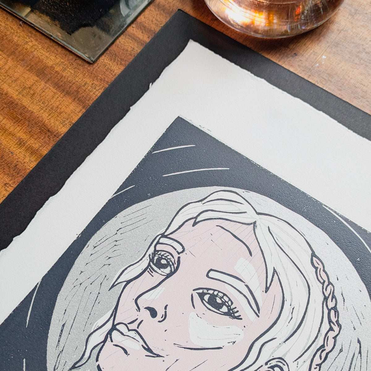 FRIGG | NORSE LOVE GODDESS linocut print showing a pale-faced woman with braided hair in black and silver ink