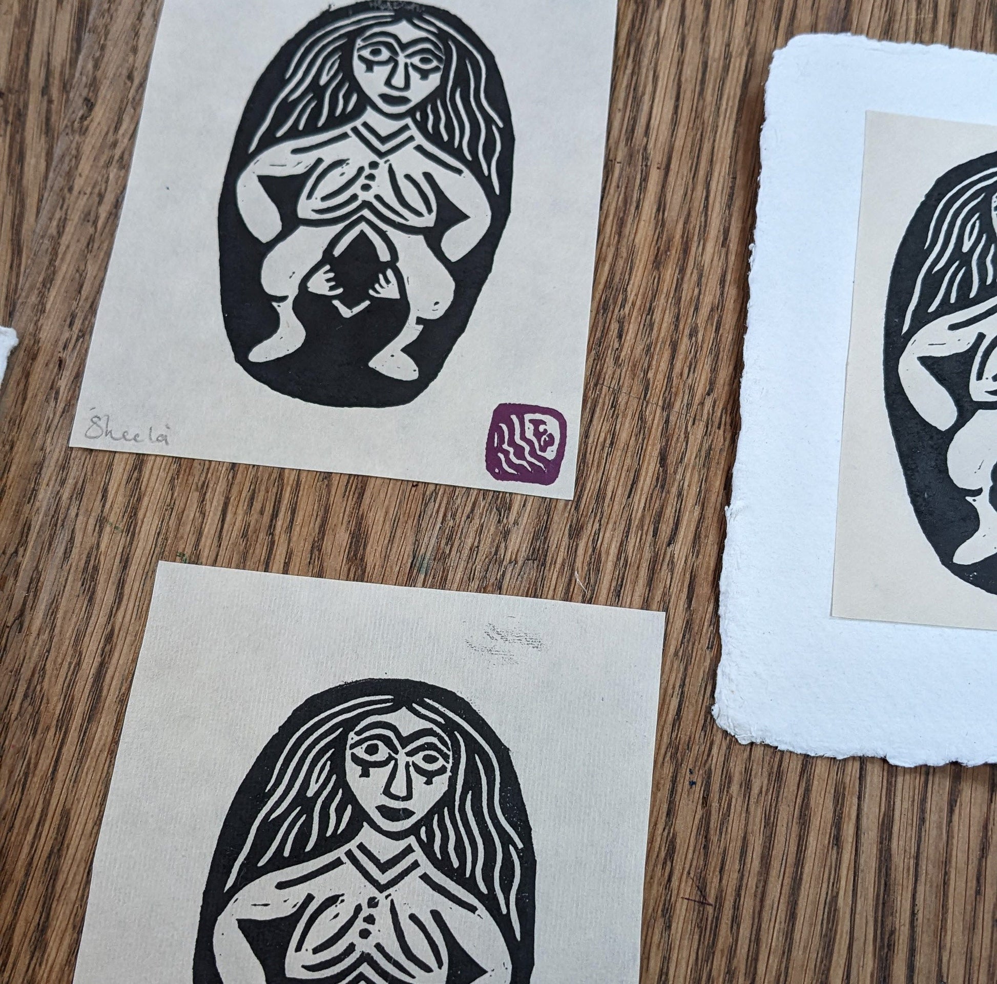 three sheela prints lying on a wooden table