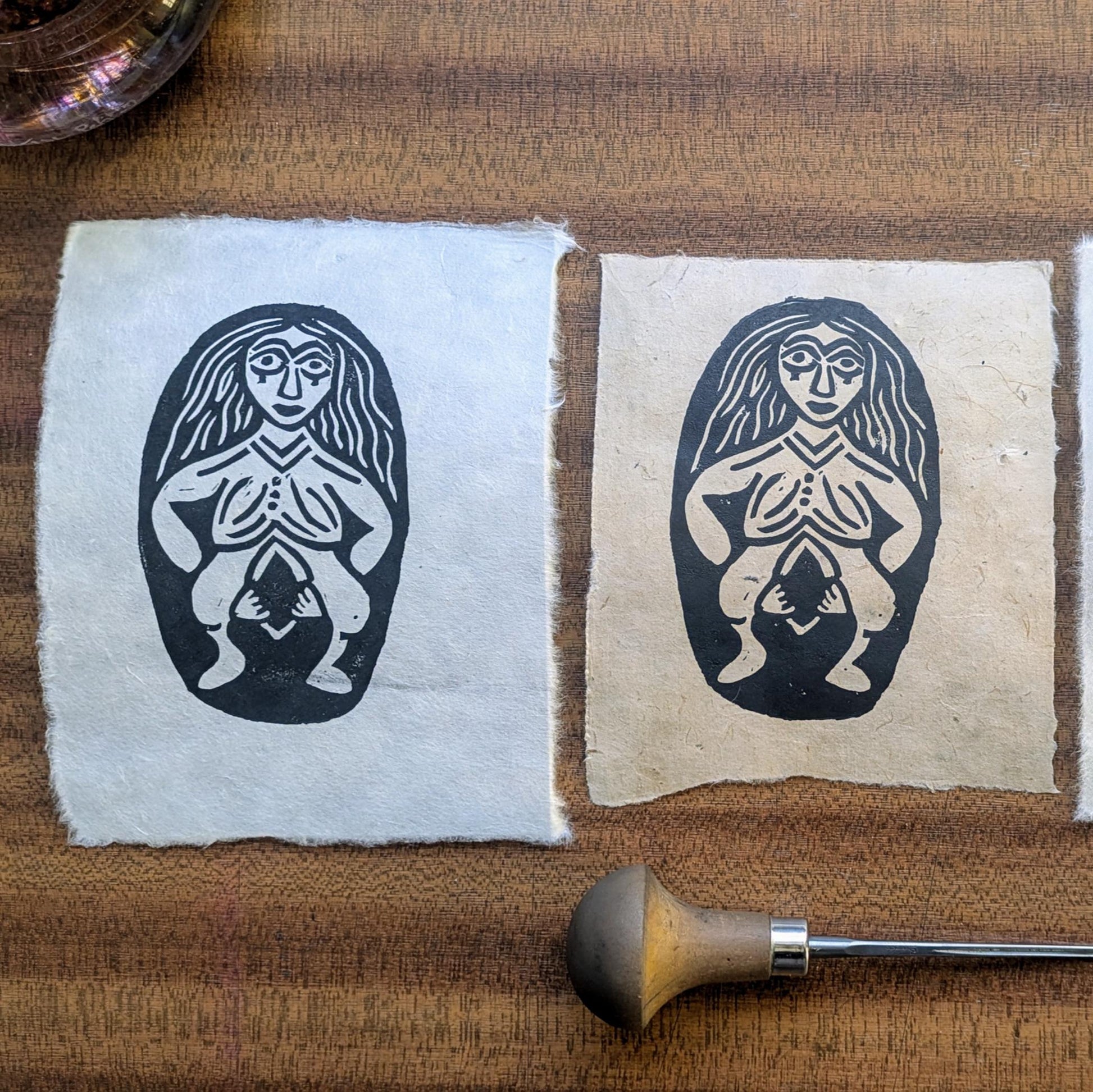 three sheela na gig linocut prints in a row