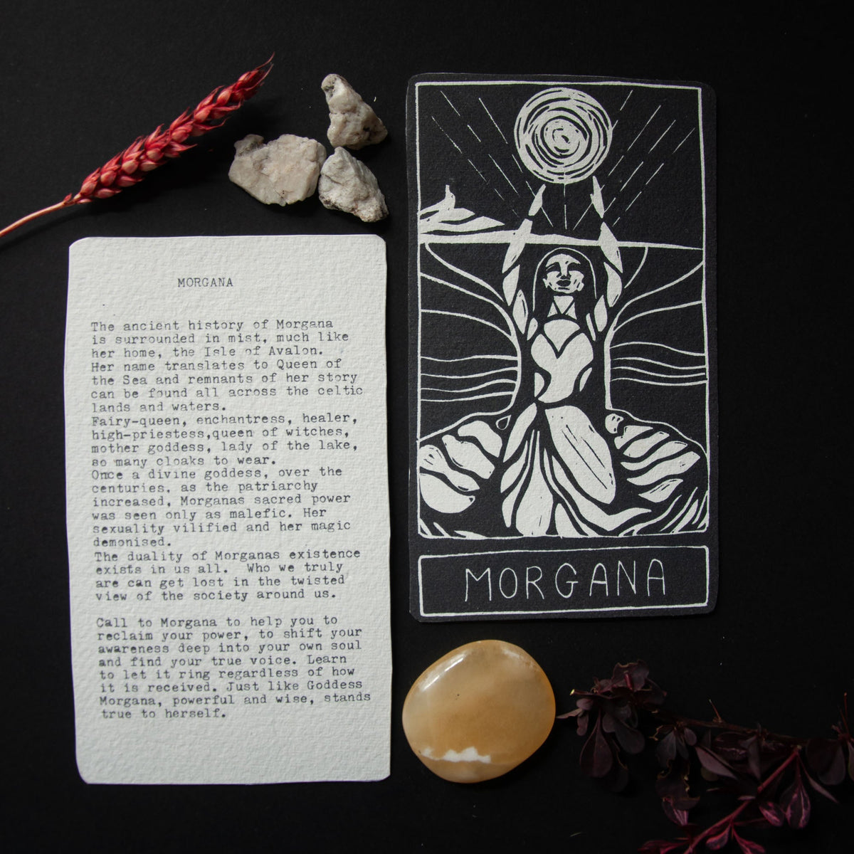 MORGANA ORACLE CARD with black-and-white linocut goddess artwork, white lettering, and a printed mythology and guidance card back