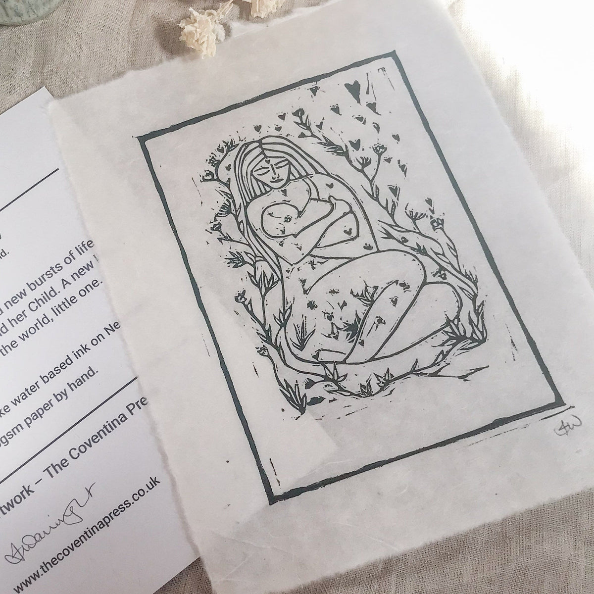 MOTHER AND BABE linocut print in dark green ink, showing a mother cradling her baby among leafy branches