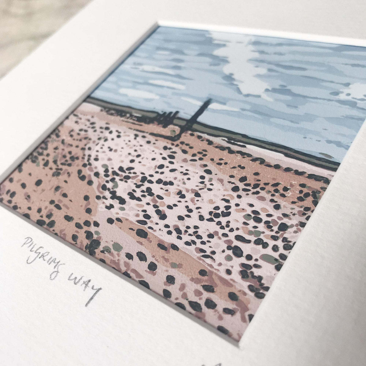PILGRIM'S WAY linocut print with a blue sea, pale sky and pink rocky shoreline dotted with dark stones