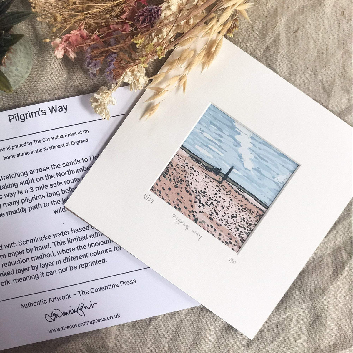 PILGRIM'S WAY linocut print with a pale blue sky and pink sandy path dotted with dark marks, mounted in cream