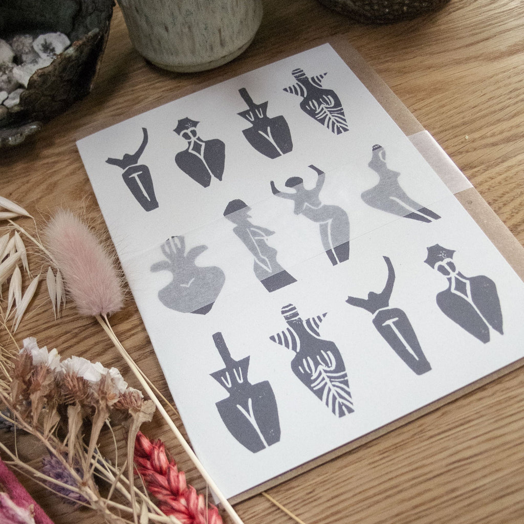 PREHISTORIC GODDESS GREETING CARD featuring a black and grey linocut pattern of stylized ancient female figures on white cardstock.