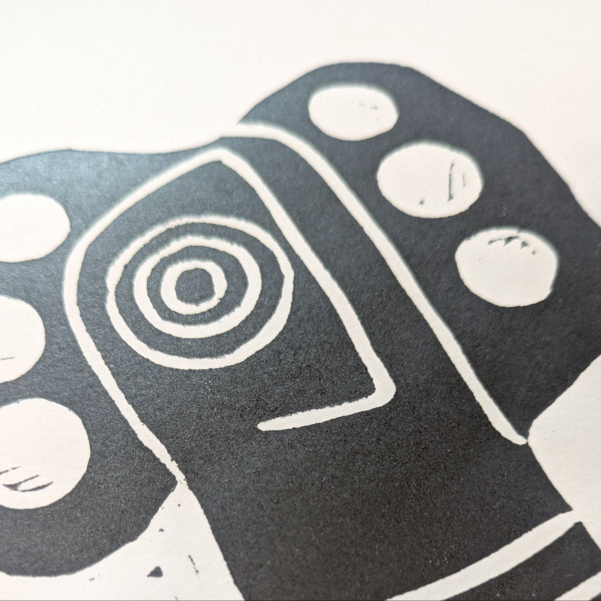 THE BIRD HEADED MOTHER black linocut print showing a stylized bird-headed figure with bold concentric eye markings