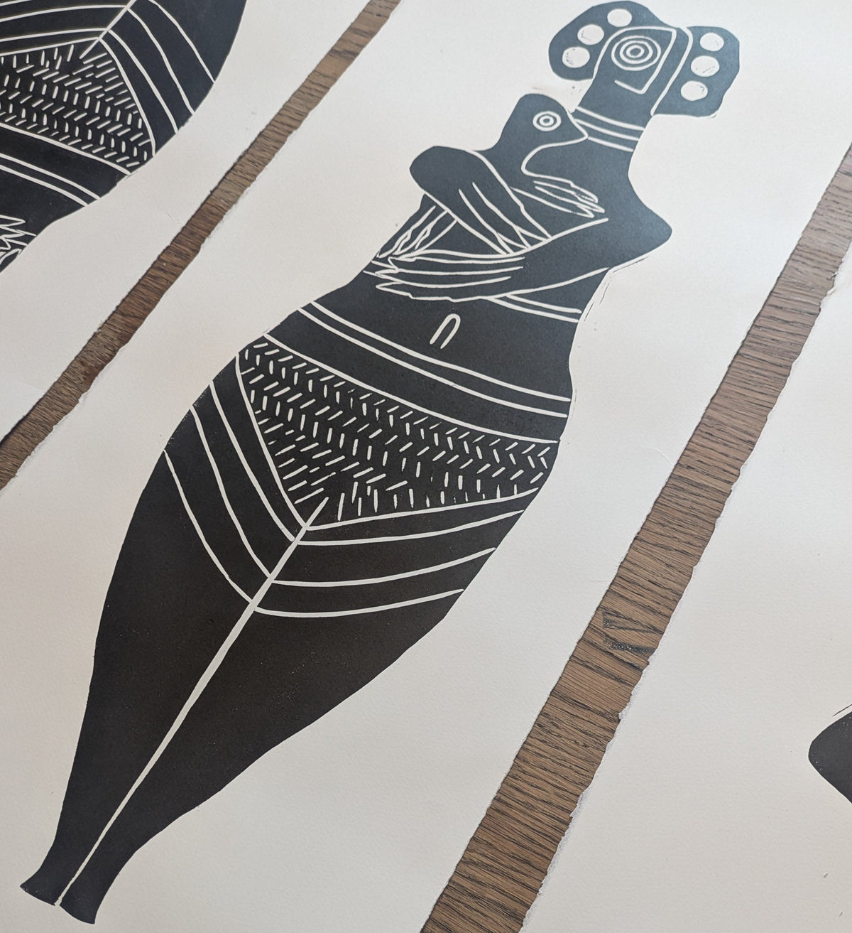 THE BIRD HEADED MOTHER linocut print in black, depicting a patterned bird-headed mother holding a small child