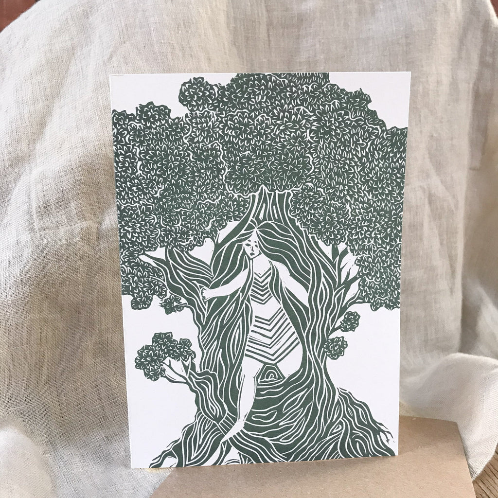 Greeting card featuring THE DRYAD, a dark green and white linocut of a woman among tree roots and foliage.