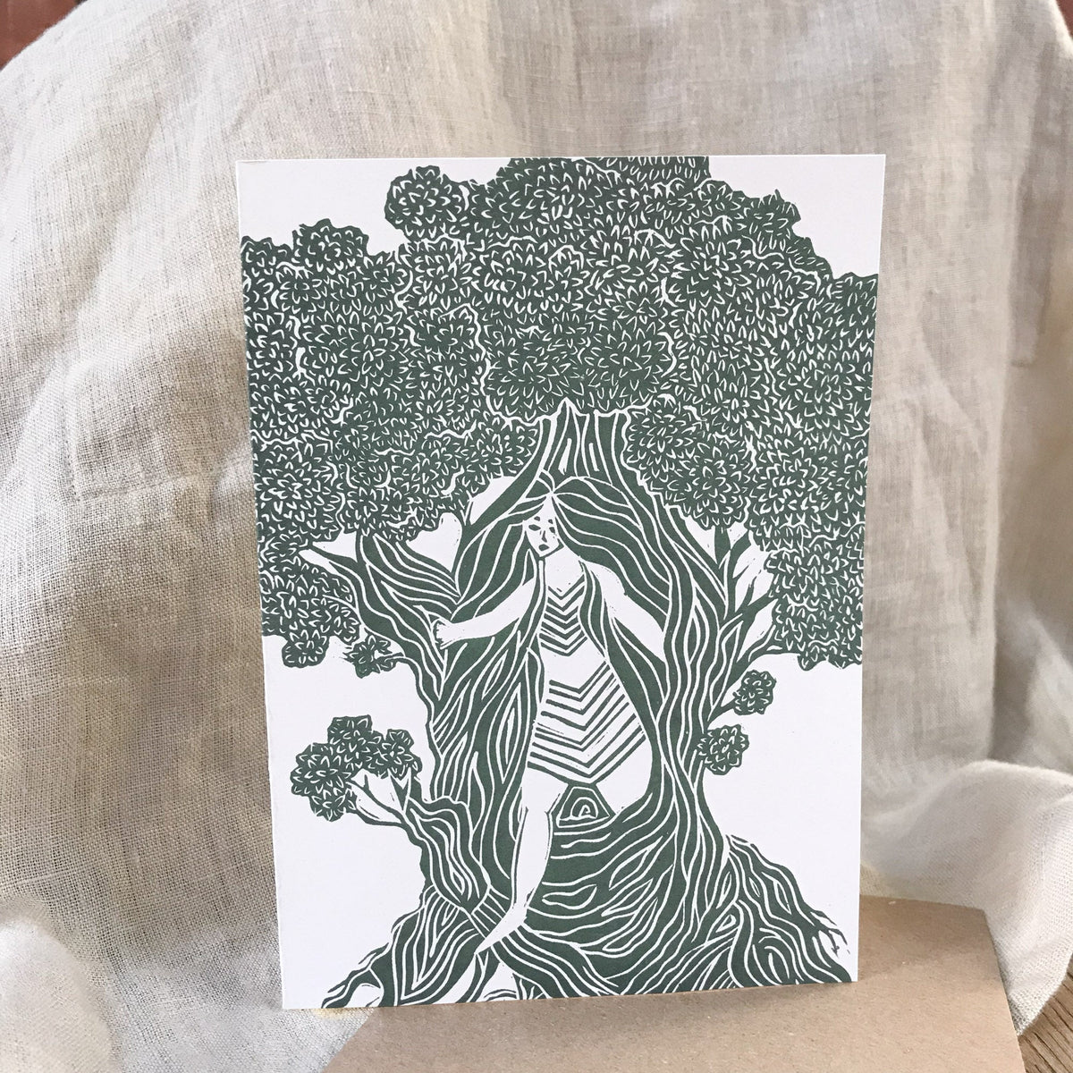 Greeting card featuring THE DRYAD, a dark green and white linocut of a woman among tree roots and foliage.