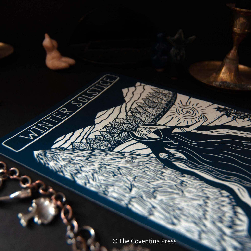 WINTER SOLSTICE altar card with a cream and dark blue linocut print of a cloaked figure, sun and mountains