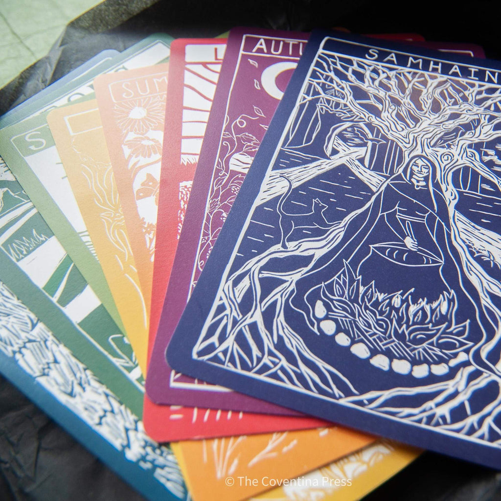 WINTER SOLSTICE altar card among colourful Wheel of the Year cards, featuring a white linocut of a robed figure